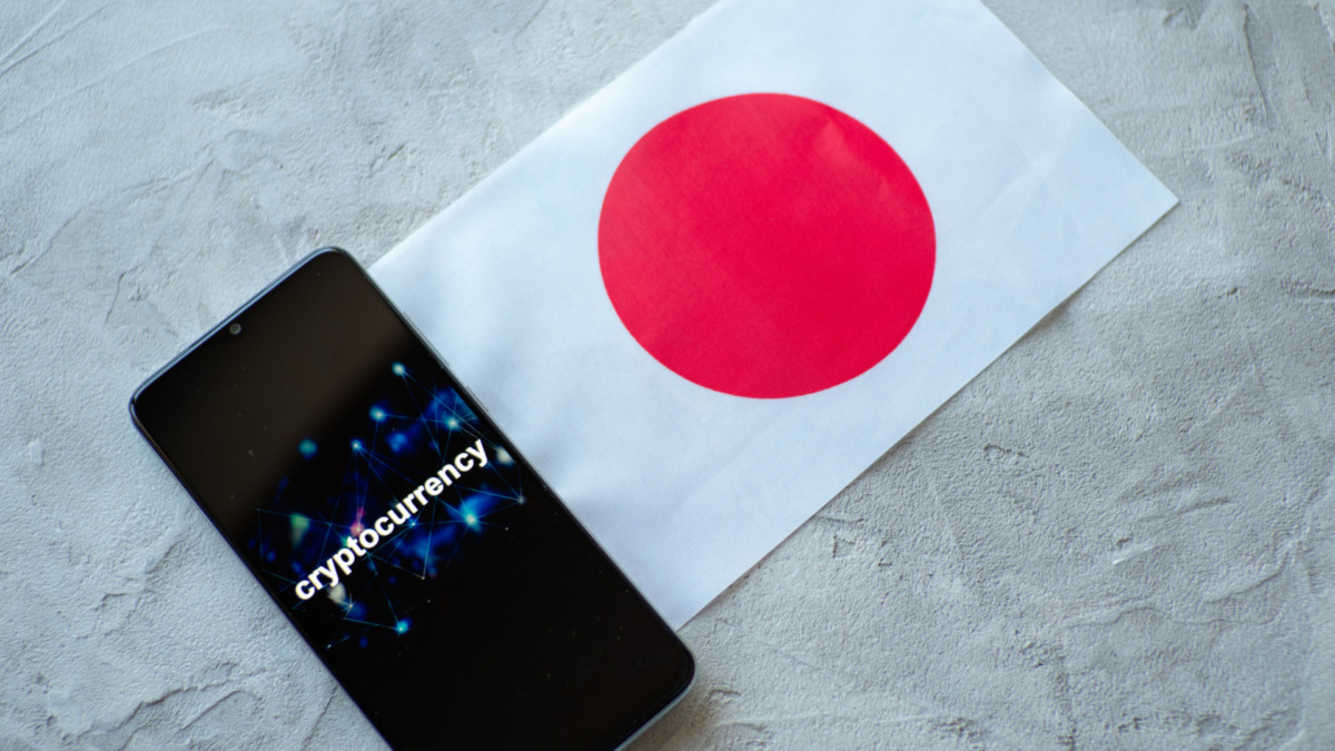 Cryptocurrency and government regulation, concept. Modern economy, smartphone with bitcoin sign on the screen on the background of the flag of Japan