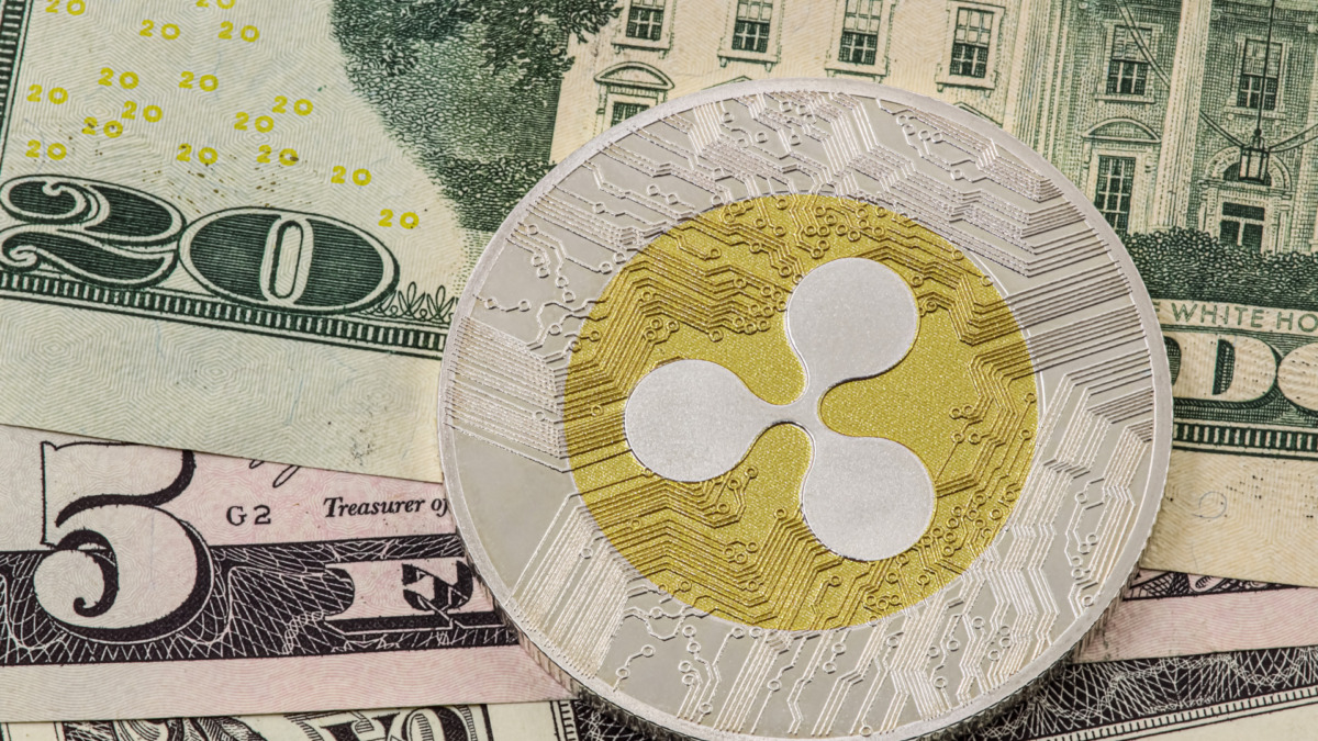 A XRP Ripple coin and American money bills in the background. USA dollars.