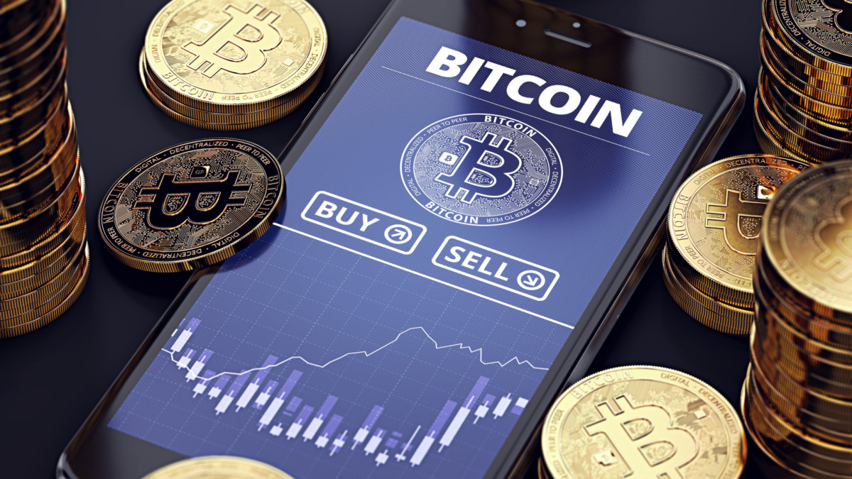 Smartphone with Bitcoin chart on-screen among piles of Bitcoins. Bitcoin trading concept. 3D rendering