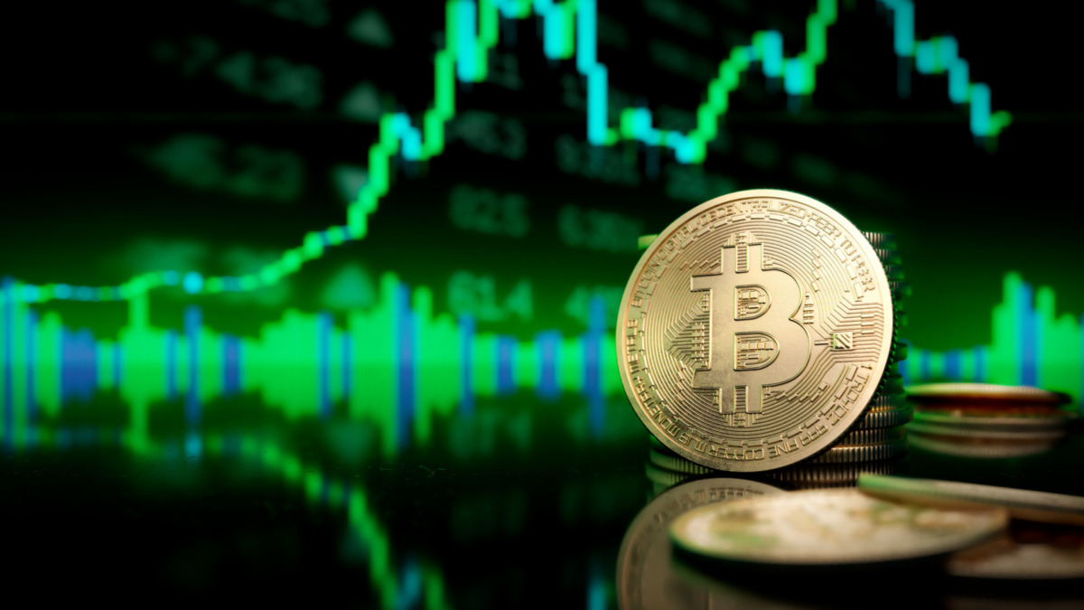 Bitcoin token standing in front of a blurred green price chart.