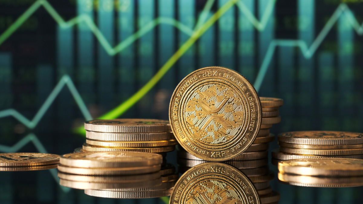 Golden XRP coins are displayed in front of green and blue financial graphs representing market trends and cryptocurrency fluctuations in a modern setting.