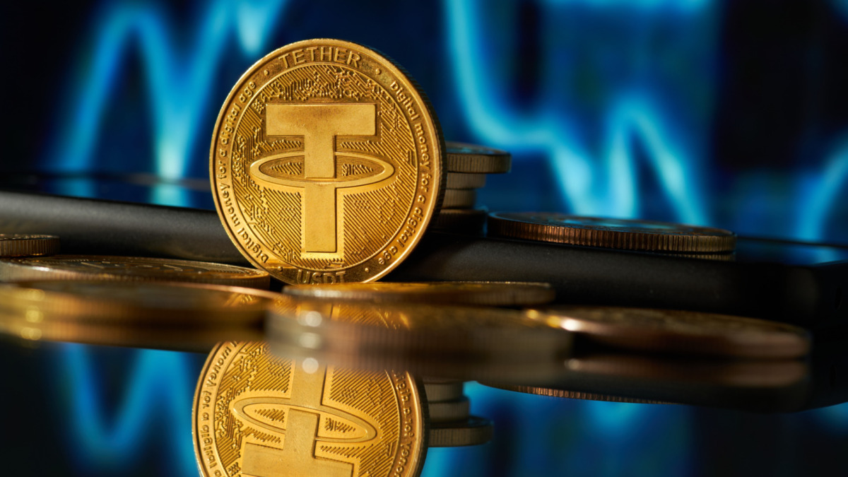 Close-up of tether cryptocurrency with blurred background of stock charts in blue color