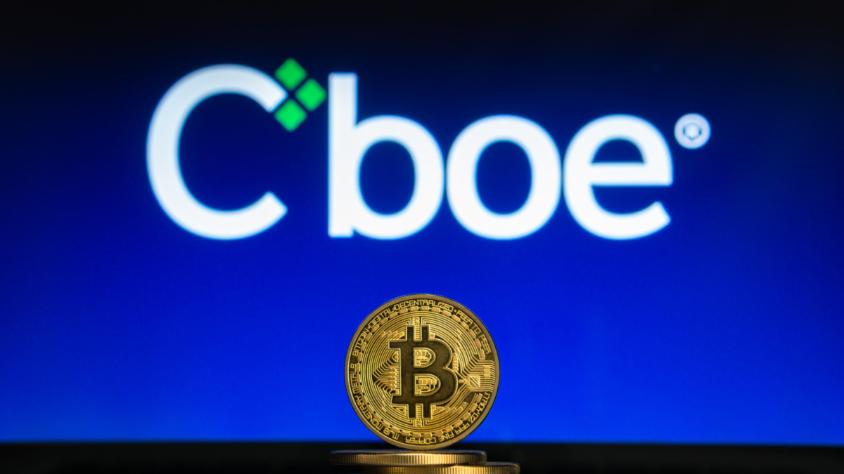 Bitcoin on a stack of coins with Cboe logo on a laptop screen. Cryptocurrency and blockchain adoption getting mainstream. Slovenia - 02 24 2019