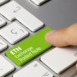 ETN Exchange traded note Written on Green Key of Metallic Keyboard. Finger pressing key.