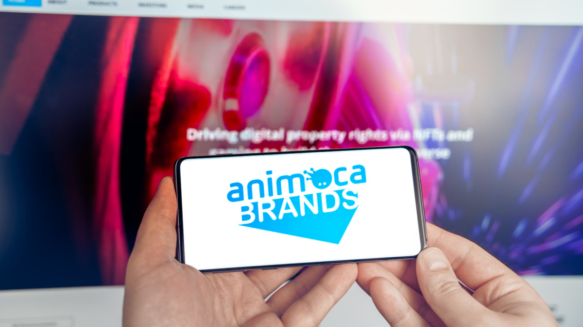 Logo of company Animoca Brands. Production of applications, crypto games. Buy land in virtual world. Blockchain nft cryptocurrency strategy.Man with mobile phone.Play-to-earn.