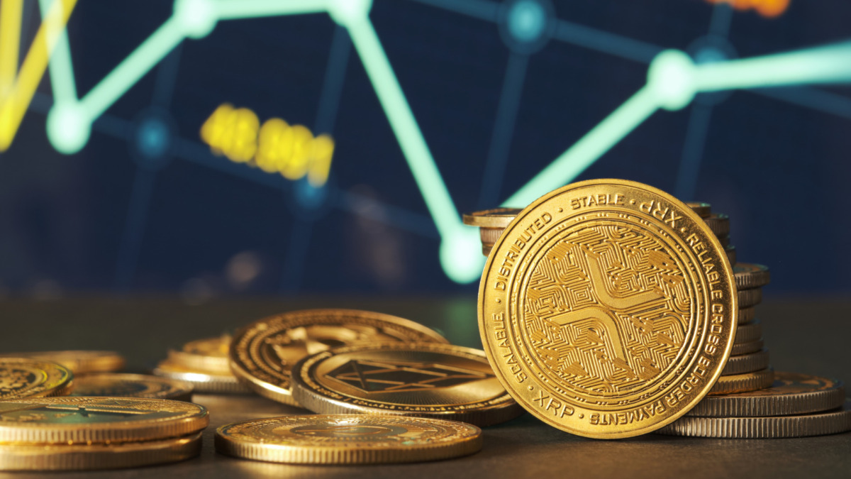 Golden XRP coins are displayed in front of green and blue financial graphs representing market trends and cryptocurrency fluctuations in a modern setting.