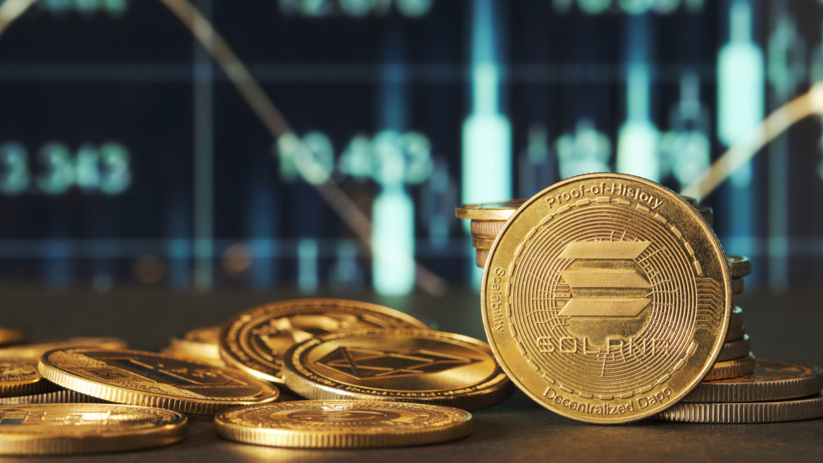 Golden Solana coins are displayed in front of green and blue financial graphs representing market trends and cryptocurrency fluctuations in a modern setting.