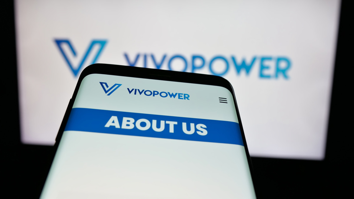 Mobile phone with logo of energy company VivoPower International plc on screen in front of website. Focus on top-left of phone display.