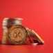 A stack of shiny XRP coins stands against a vibrant red background. The coins have a popular dog design, highlighting the rise of digital currency.