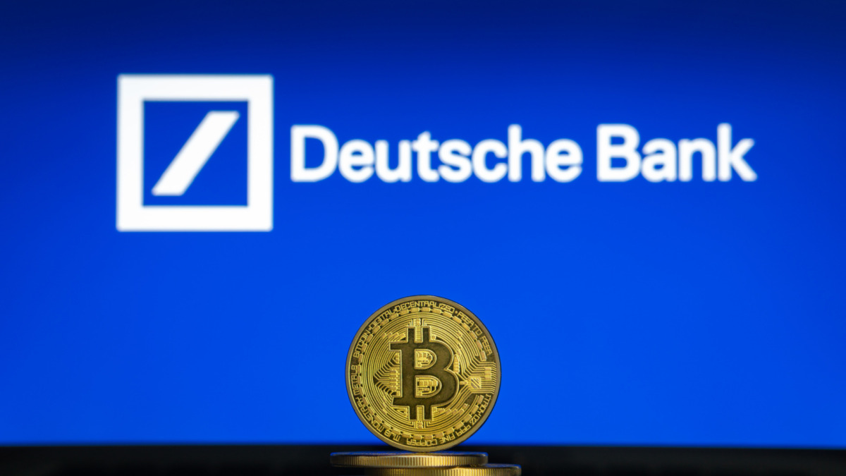 Bitcoin on a stack of coins with Deutsche Bank logo on a laptop screen
