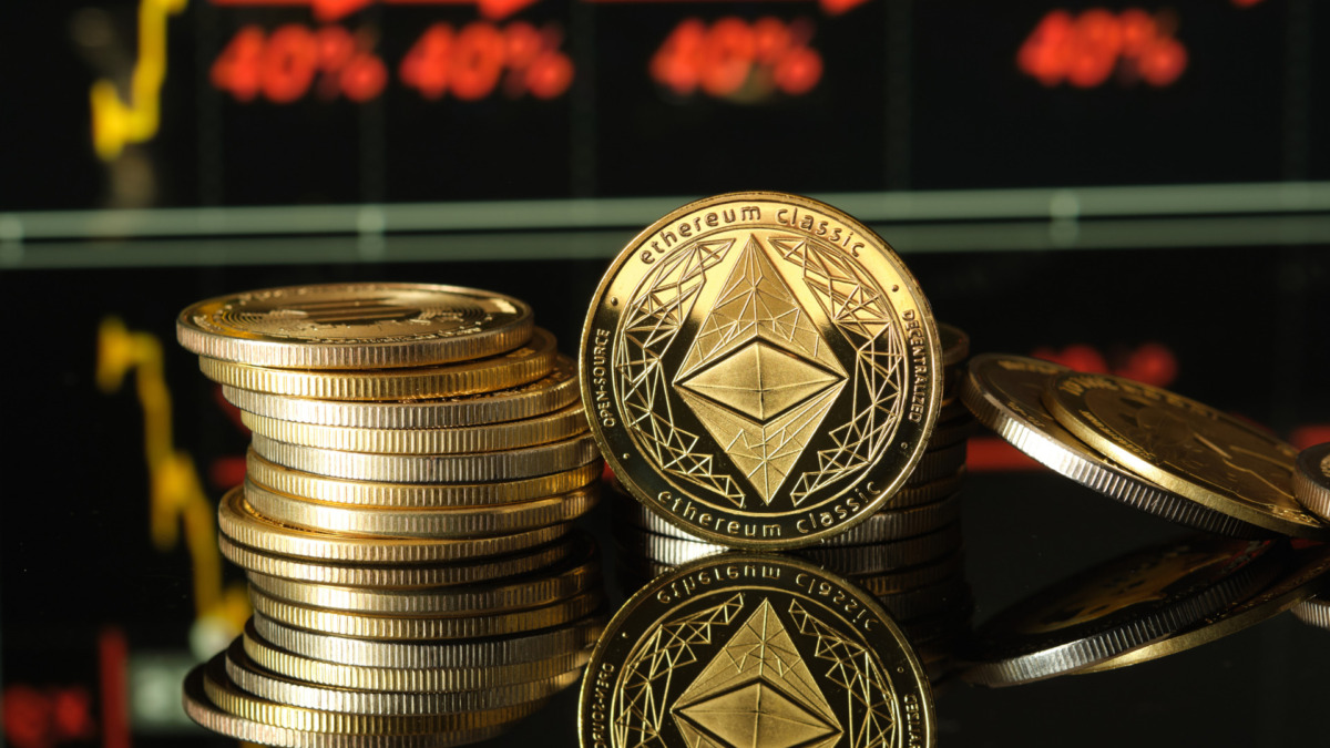 Piles of shiny ethereum coins are elegantly arranged on a reflective surface, while charts show cryptocurrency trends in the background