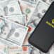 Binance mobile application of global blockchain ecosystem, cryptocurrency exchange. Binance logo on screen of smartphone lying on money background. Top view, copy space. Smolensk, Russia 28.02.2022.