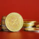 A collection of gold XRP cryptocurrencies is prominently displayed against a bright red background. The coins represent digital currency concepts and emphasize finance and investment.