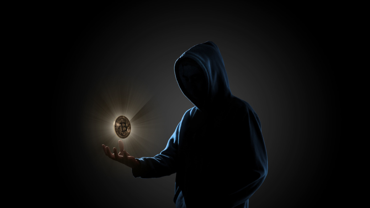 Golden Bitcoin floating above of hacker's hand in dark background. Finance, business, e-commerce or cyber crime concept
