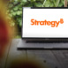 The new MicroStrategy (Strategy Inc.) logo shown on a MacBook Pro screen, representing innovation and modern business technology.
