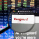 Vanguard company logo on a website with blurry stock market developments in the background, seen on a computer screen through a magnifying glass