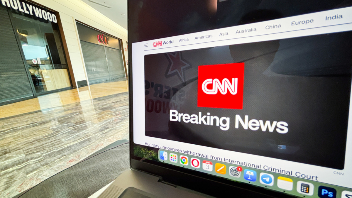 CNN Breaking News displayed on a laptop screen in a modern shopping mall environment showcasing technology and media influence concept