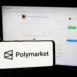 Person holding smartphone with logo of crypto prediction market company Polymarket on screen in front of website. Focus on phone display.