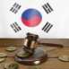 Court gavel and golden bitcoins on the flag of South Korea. Illustration of the concept of blocking foreign crypto exchanges lacking permit