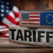Two metallic blocks, one with the US flag and the other with the EU flag, are stacked on a wooden surface with a "TARIFFS" sign in front.
