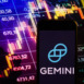 Smartphone displaying logo of Gemini cryptocurrency exchange on stock exchange diagram background