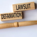 DEFAMATION LAWSUIT - words on wooden blocks on a white background with a judge's gavel.