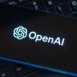 Hand pointing at SearchGPT page seen on the smartphone and official OpenAI company logo on background. New AI search tool.