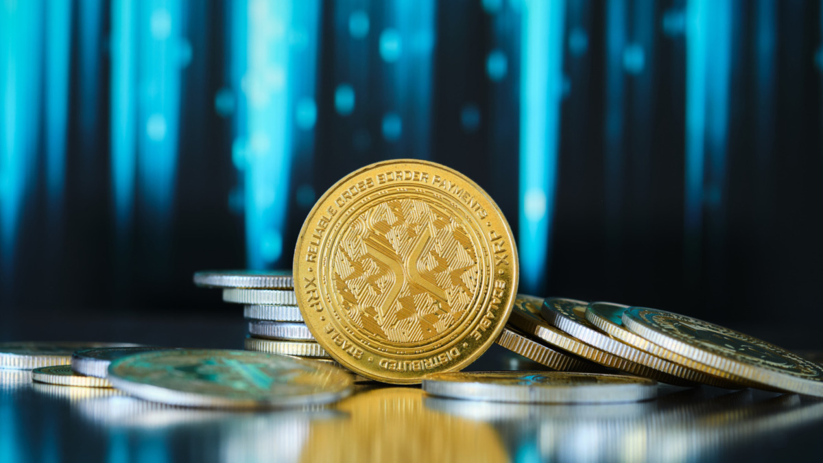 Xrp cryptocurrency. Inscribed gold coins are stacked on a reflective surface, while colorful financial graphs show trends in the background, suggesting investment themes.